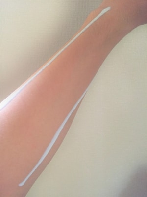腕や足など広範囲な部分に塗るなら、このように筋状に肌においてから手のひらで伸ばすといい